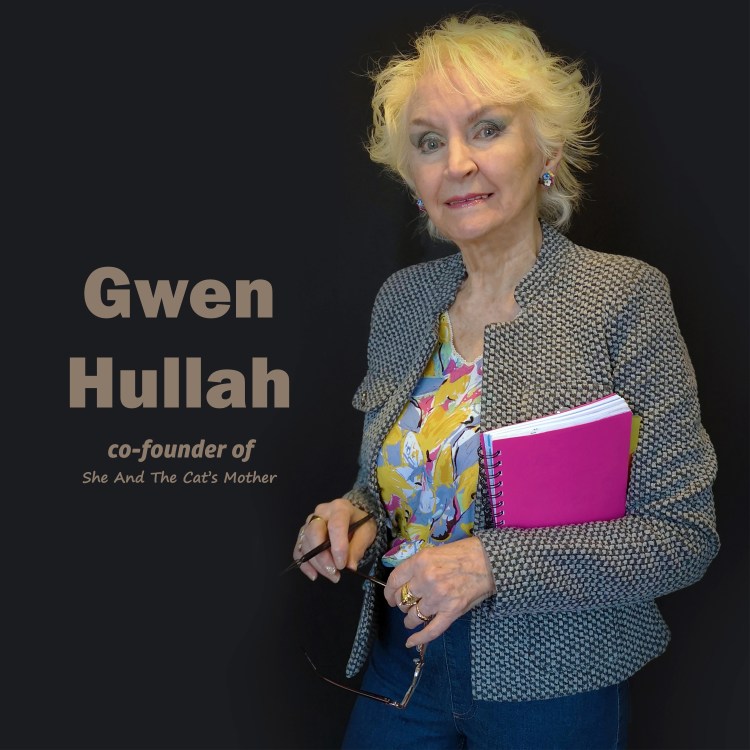 Image shows Gwen Hullah of She And The Cat's Mother book publishers, smiling while looking to camera, she's holding a notepad, pen and reading glasses.